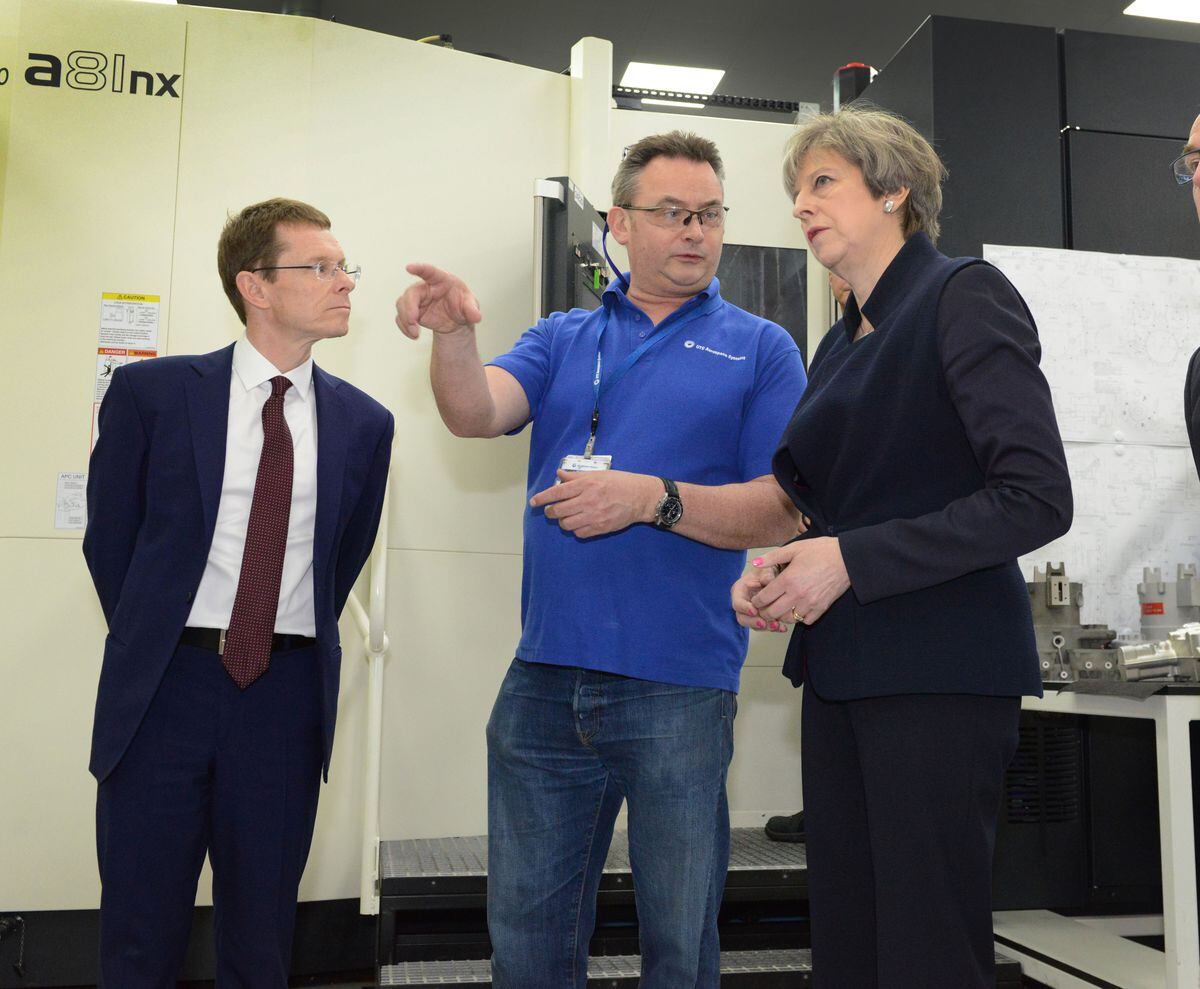 Prime Minister Theresa May, talks to worker Kevin Nicholls, of Cheslyn Hay, with, left, West Midlands Mayor Andy Street watching on