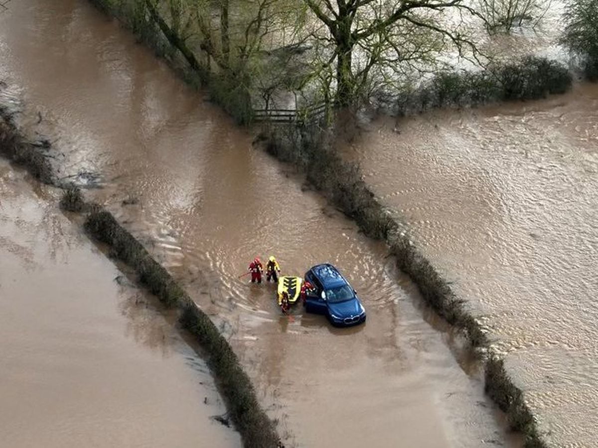 Dramatic photo shows woman being rescued after car gets stuck in flood water 