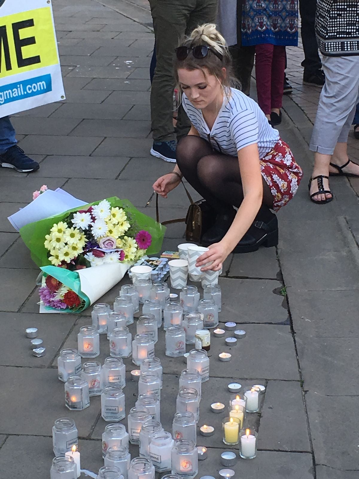 A young girl lays a candle at the vigil