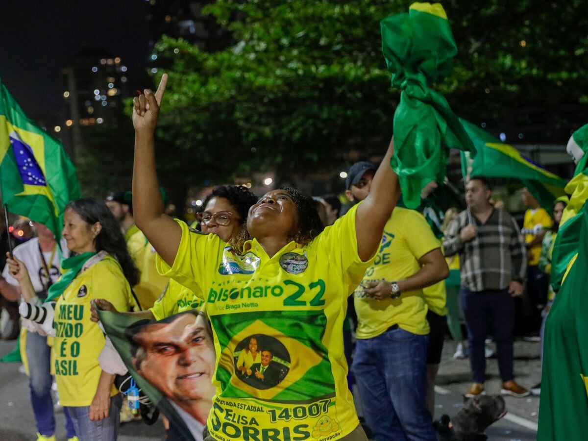 Supporters of Brazilian President Jair Bolsonaro, who is running for another term, celebrate partial results after general election polls closed outside his family home in Rio de Janeiro, Brazil on Sunday, Oct. 2, 2022