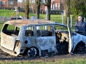 Councillor Paul Bott with the burnt out car near the play area