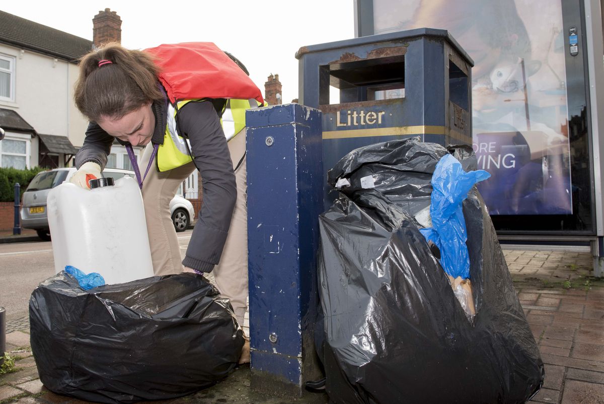 A council officer gets stuck into rubbish dumped outside shops in Blakenhall. 