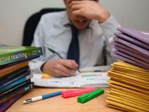 File photo of a school teacher next to piles of classroom books