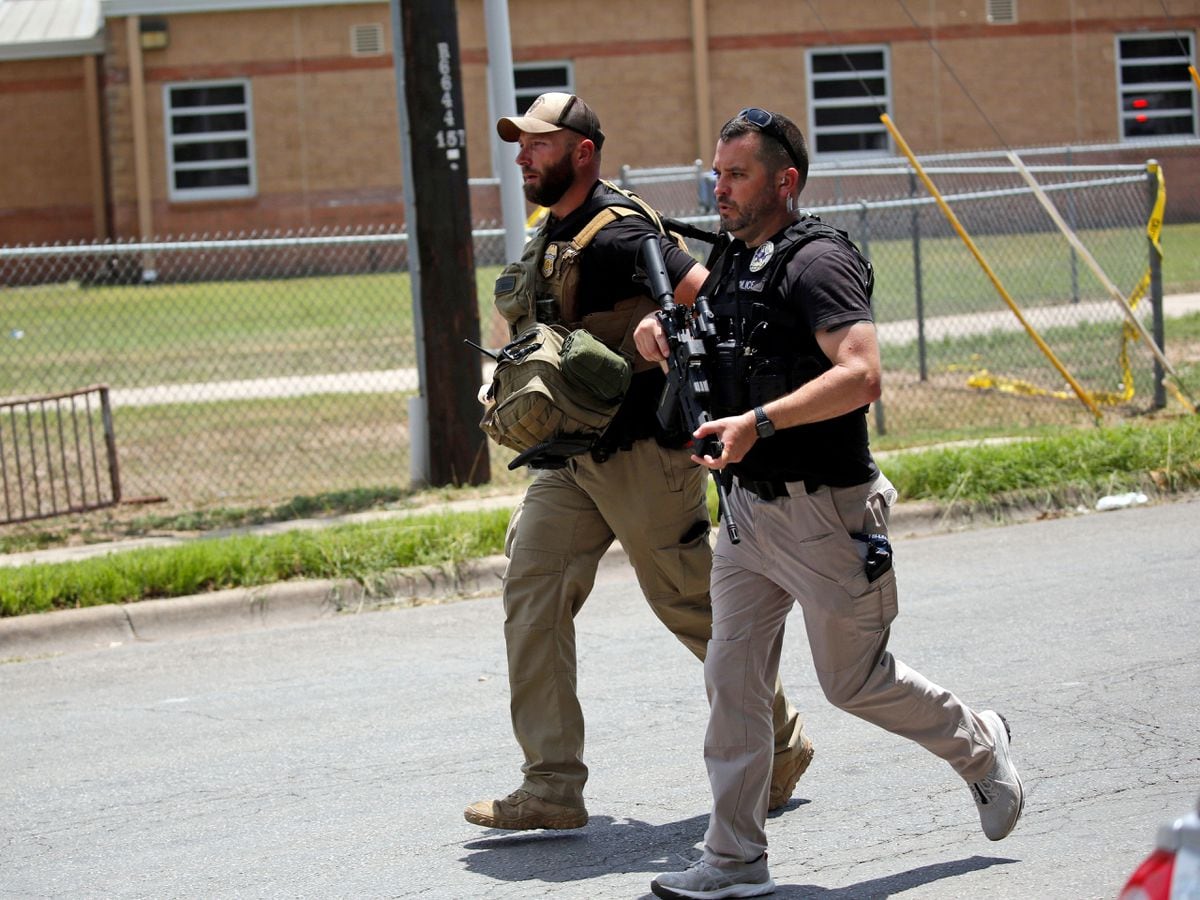 Police walk near Robb Elementary School following a shooting