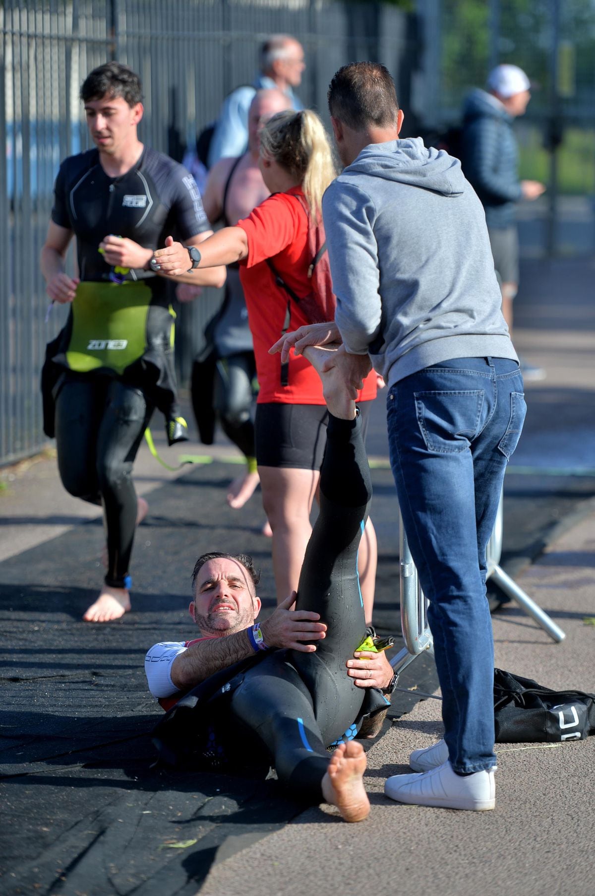 A spectator gives an exhausted triathlete cramp relief