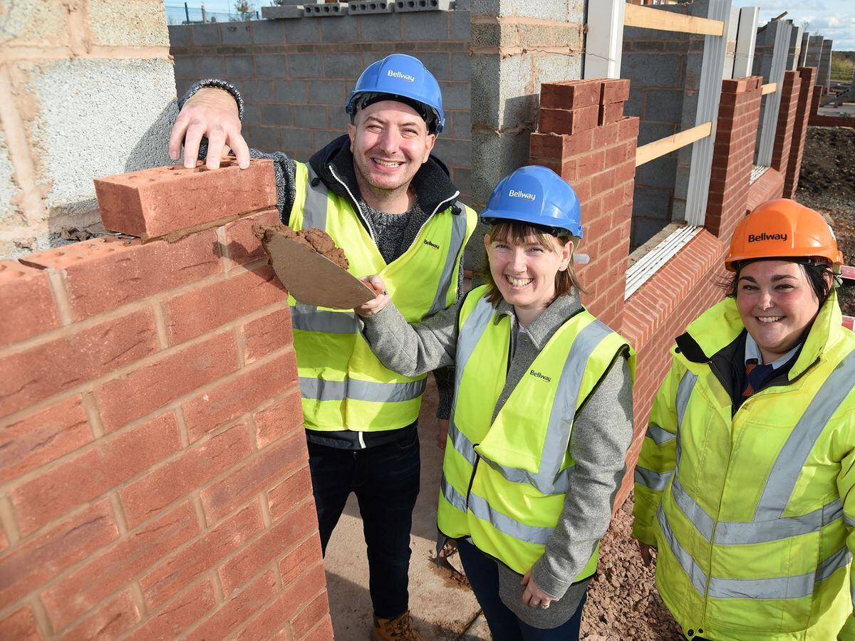 Stuart and Christine Bradley-Mold, with Assistant Site Manager Maddie Dale, lay a brick on their new home 