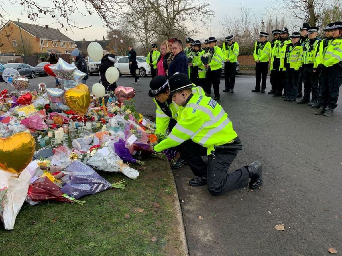Officers from West Midlands Police lay bouquets of flowers near to the scene at Babbs Mill Lake, Solihull, wher3e four boys died