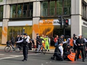 Police with Just Stop Oil protesters who have blocked Park Lane in central London and sprayed paint over a Aston Martin car showroom