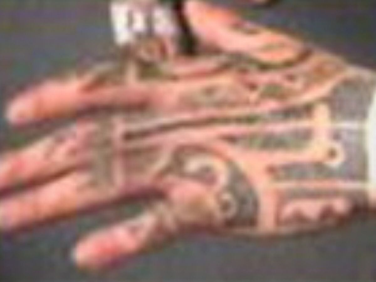 The "distinctive tribal tattoos" on his left hand.