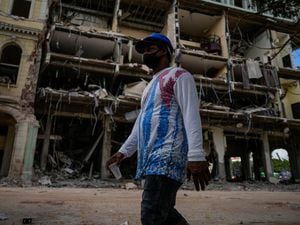 A man wearing a Cuban national flag shirt, walks past the site of Friday’s deadly explosion that destroyed the five-star Hotel Saratoga, in Havana, Cuba