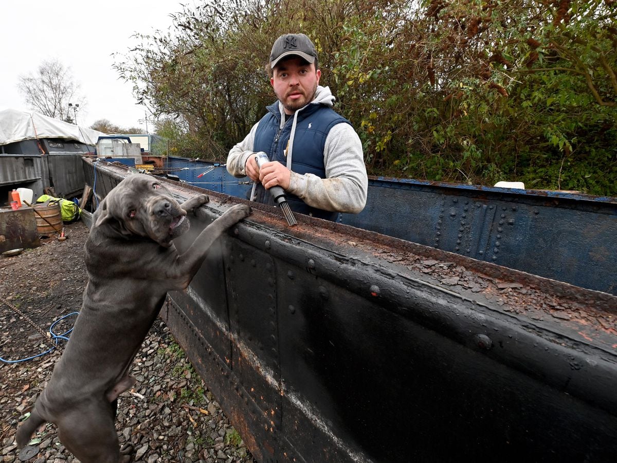 Jamie Cameron works on the historic boat with his Cane Corso dog, Drago