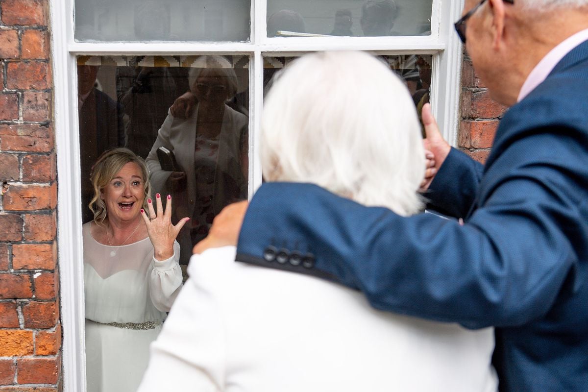 Tracie Kenny shows her wedding ring to her parents watching from outside after her marriage to Neal Arden in Ironbridge