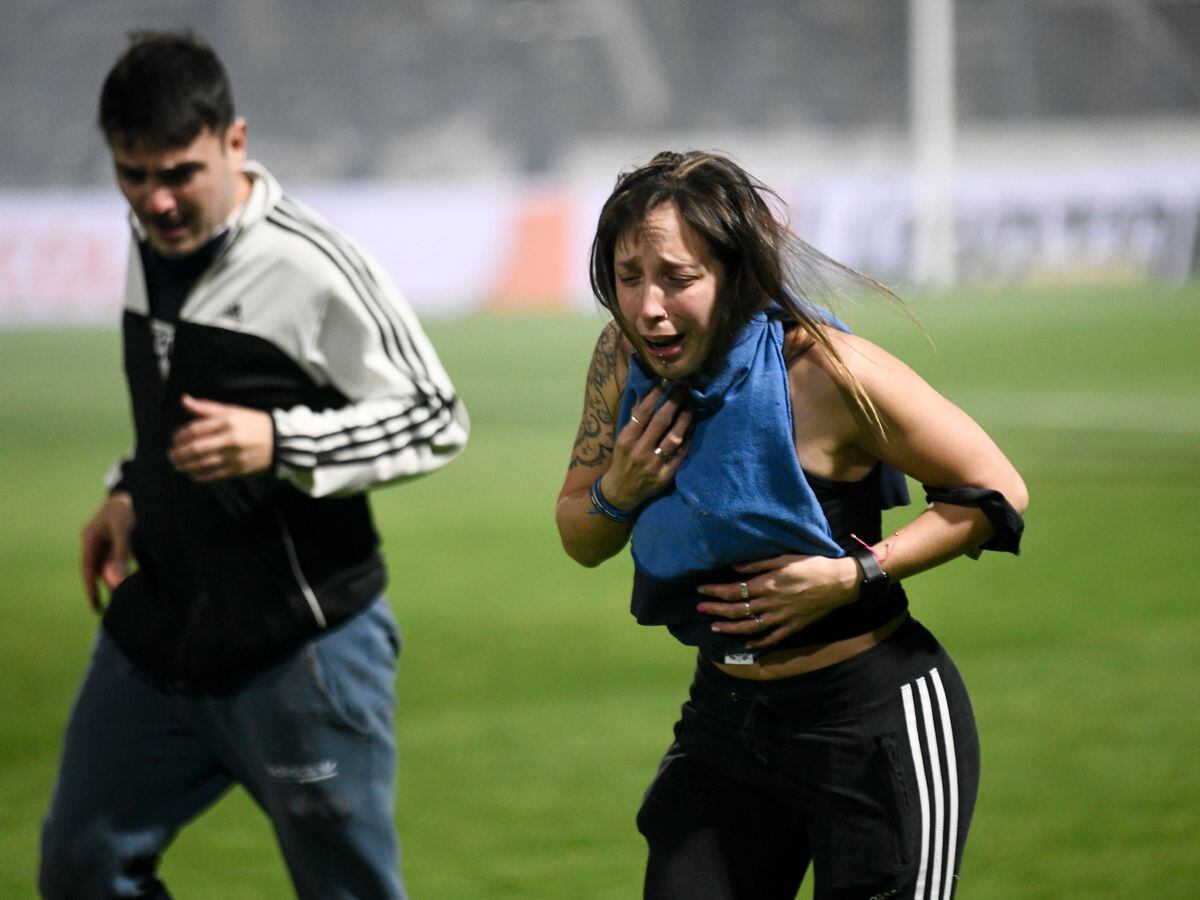 Fans runs after being tear-gassed at an Argentina football match