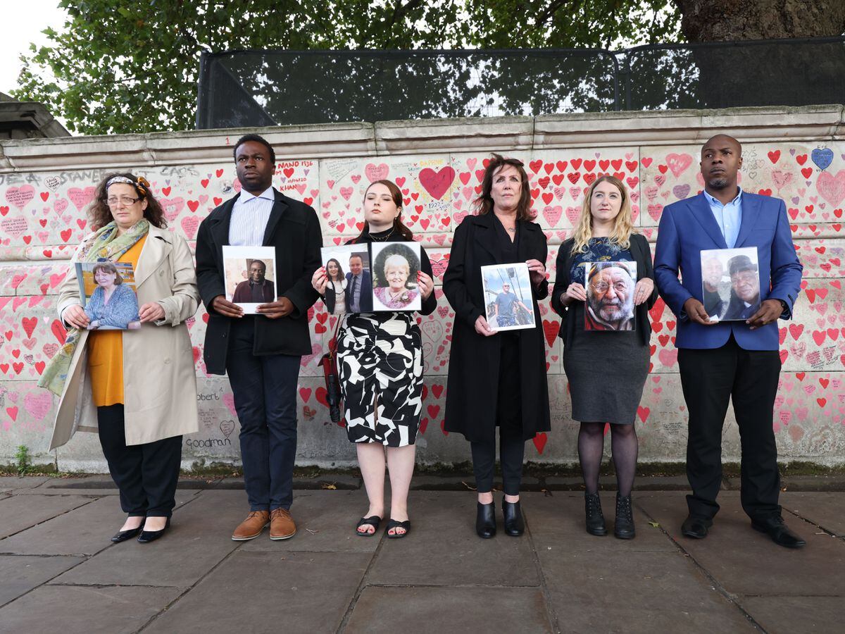 Bereaved people hold photos of loved ones lost to coronavirus (James Manning/PA)