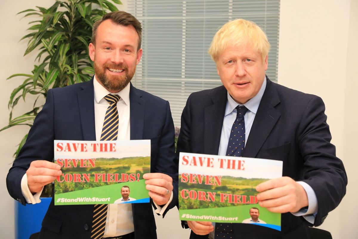 Stuart Anderson, left, with Boris Johnson, right, holding placards saying 'Save the Cornfields!'