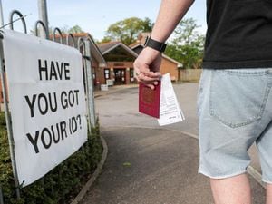 A voter carries his passport along with his poll card in Knaphill, Woking (Andrew Matthews/PA)