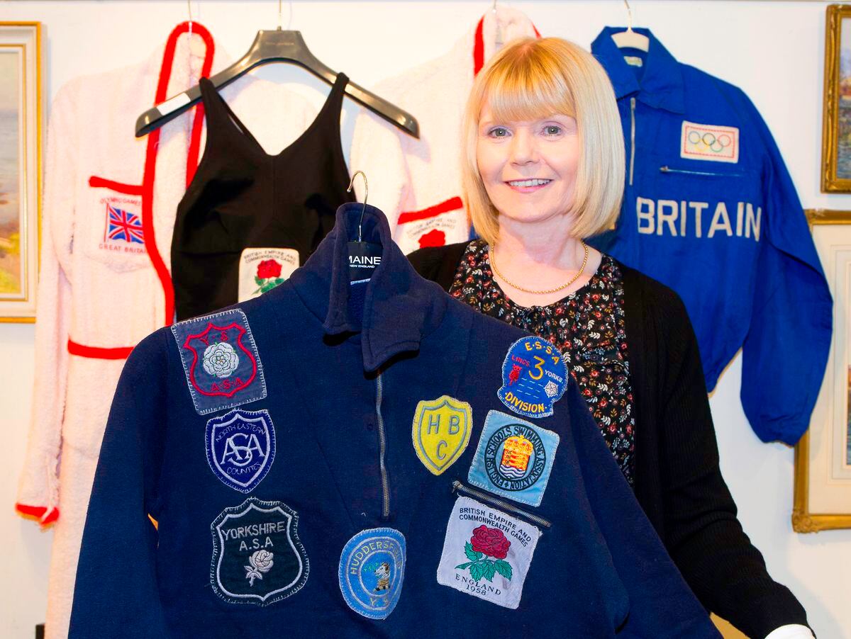 Susan Atkinson standing next to the collection, holding Anita Longbrough's first tracksuit jacket