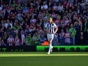 Jonas Olsson of West Bromwich Albion runs through a shaft of sunlight on the pitch.