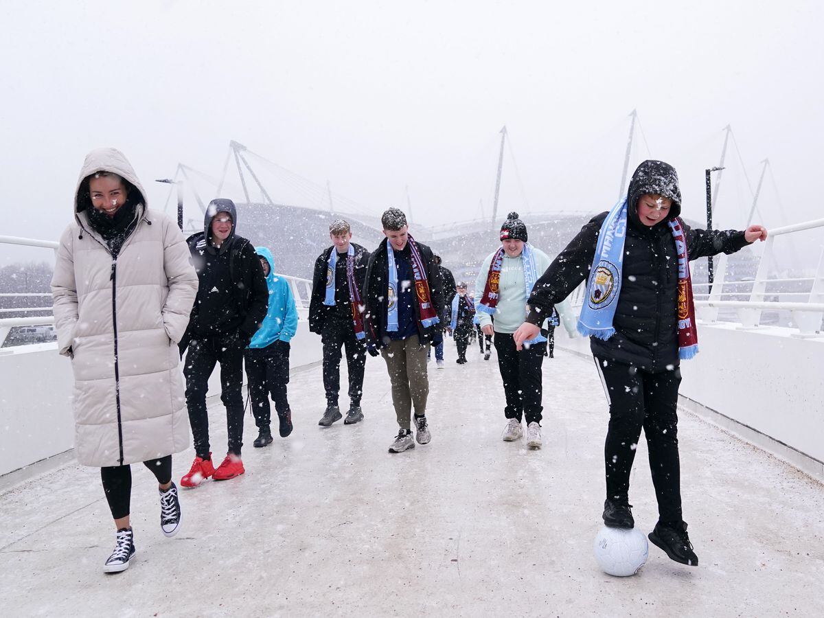Fans cross the bridge to the Etihad Stadium in the snow before Manchester City's game with West Ham
