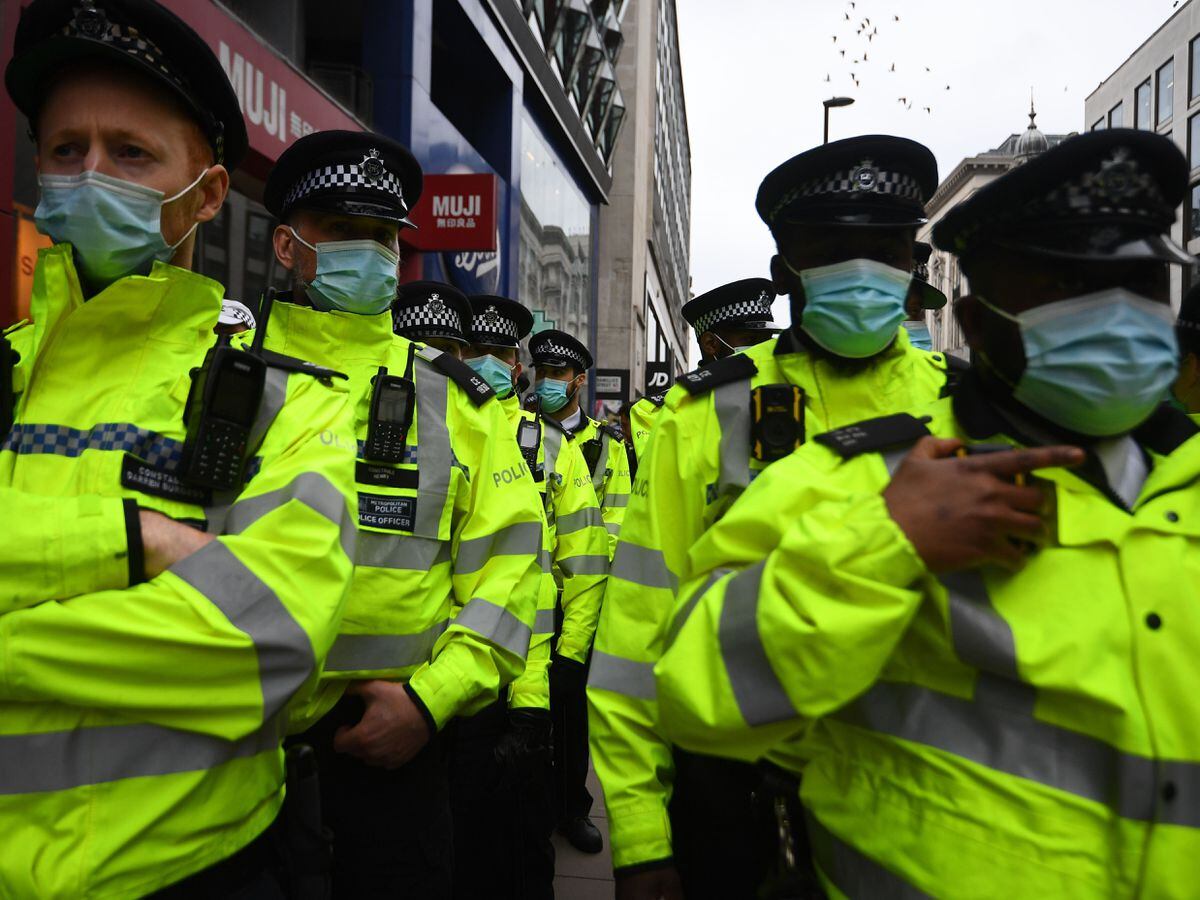 Police officers observe an anti-lockdown protest in London’s Oxford Street (PA)