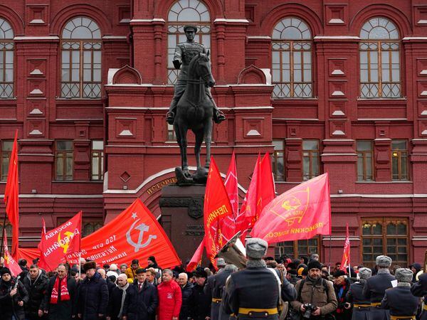 Communist party supporters with red flags gather around the statue of Soviet Marshal Georgy Zhukov after a wreath-laying ceremony at the Tomb of the Unknown Soldier near the Kremlin Wall