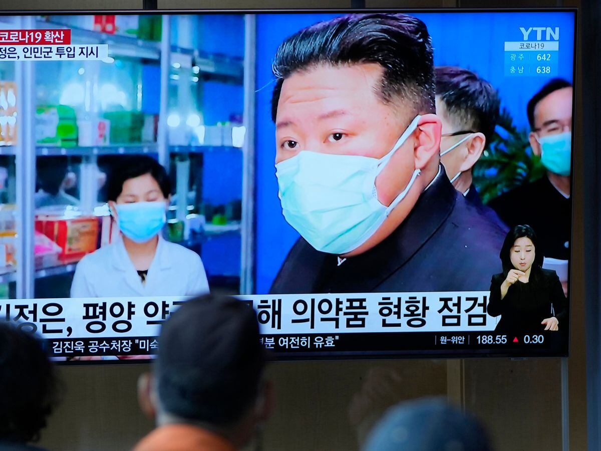 People watch a TV screen showing a news program reporting with an image of North Korean leader Kim Jong Un