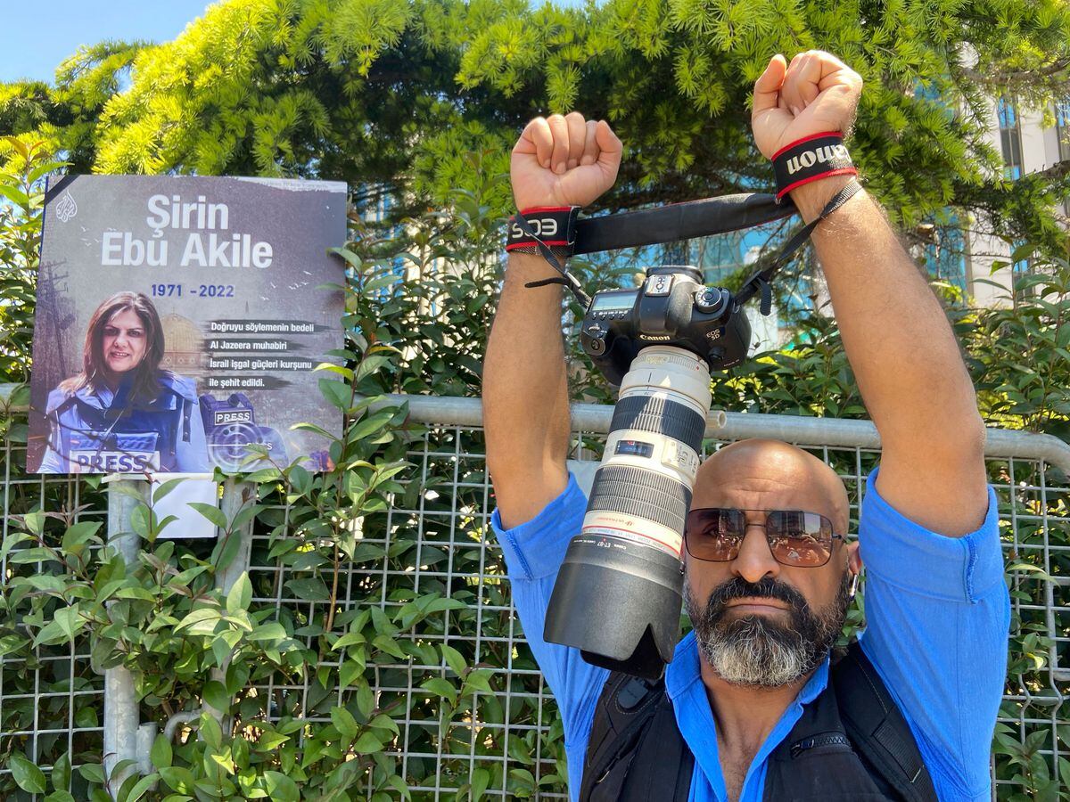Ibrahim Almasri, an Egyptian freelance photographer, wraps his camera straps around his wrists like handcuffs during a protest as dozens of pro-Palestinian demonstrators gathered near the Israeli Consulate in Istanbul, Turkey, on Thursday to denounce the death of Al Jazeera journalist Shireen Abu Akleh. Akleh