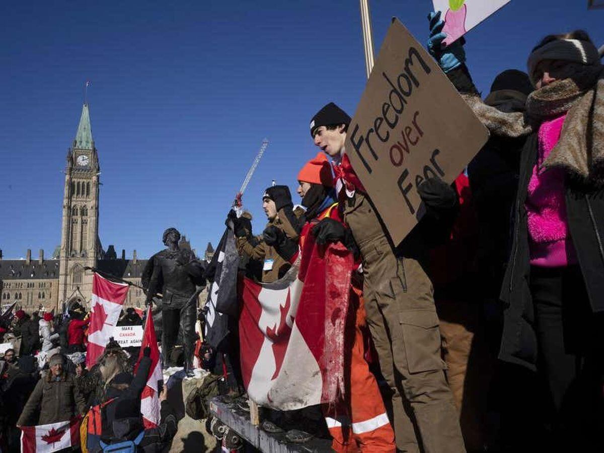 Protesters participating in a cross-country truck convoy protesting measures taken by authorities to curb the spread of COVID-19 and vaccine mandates gather near Parliament Hill in Ottawa on Saturday.