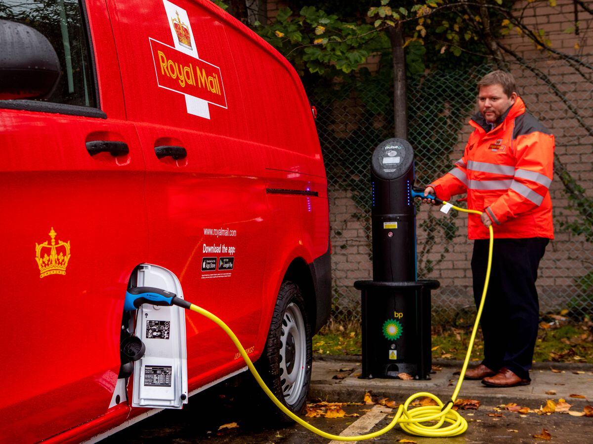 A Royal Mail worker charges an electric van