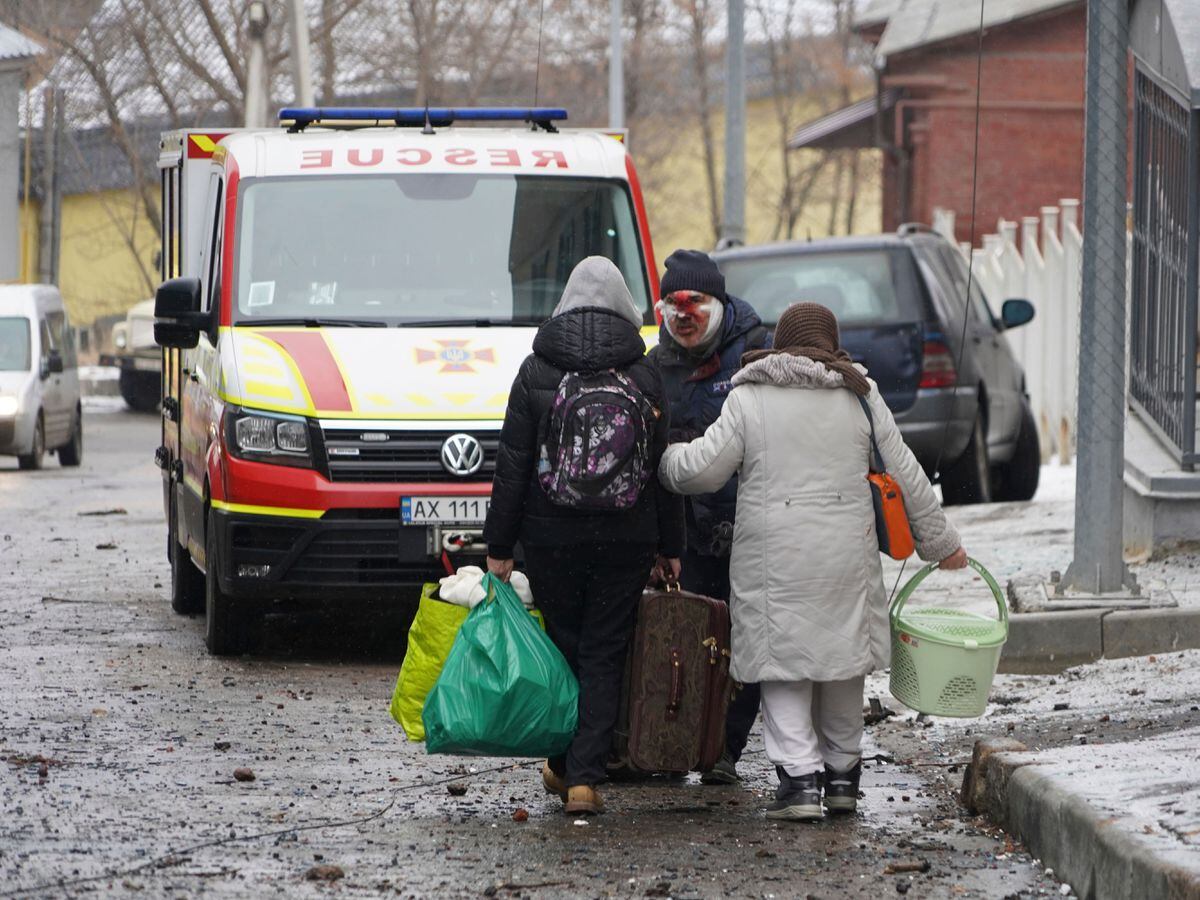 An injured man evacuates with family members from a residential building which was hit by a Russian rocket at the city centre of Kharkiv, Ukraine
