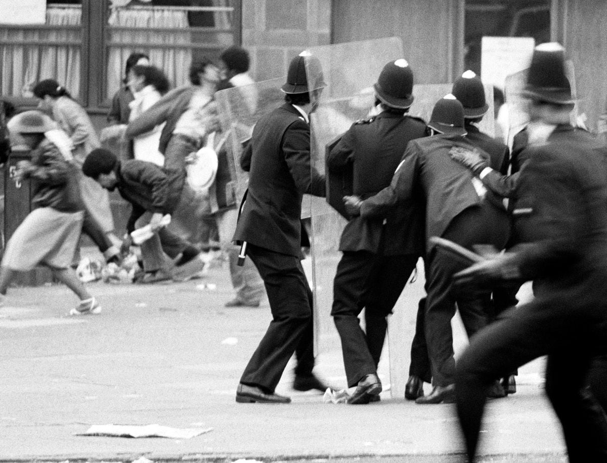 Police armed with riot shields, huddling together for protection as violence flared near Lambeth Town Hall in Acre Lane, Brixton