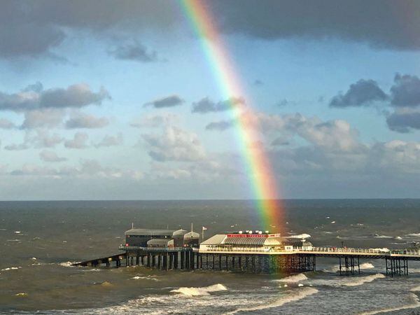 A rainbow is seen hanging over the pier in Cromer, Norfolk (Laura Kerr/PA)