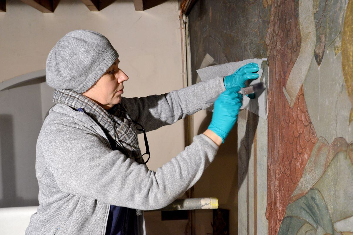 Conservation expert Lisa Shekede works on one of the paintings
