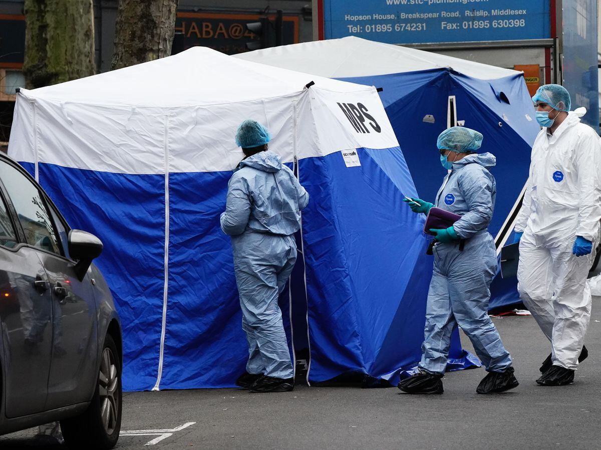 Metropolitan Police officers in forensic suits next to tents at the scene on Monday