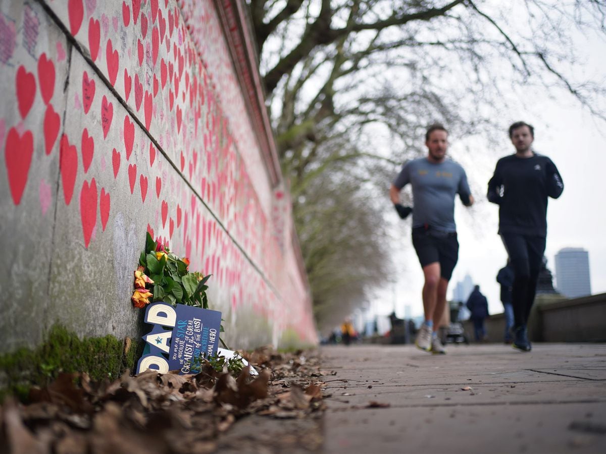 People jog past the Covid memorial wall near St Thomas’ Hospital in London (Yui Mok/PA)