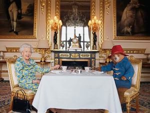 Queen Elizabeth II and Paddington Bear in a film for the BBC Platinum Party at the Palace. She is pictured here with one of her Launer handbags, which she pulls a marmalade sandwich out of during the sketch.