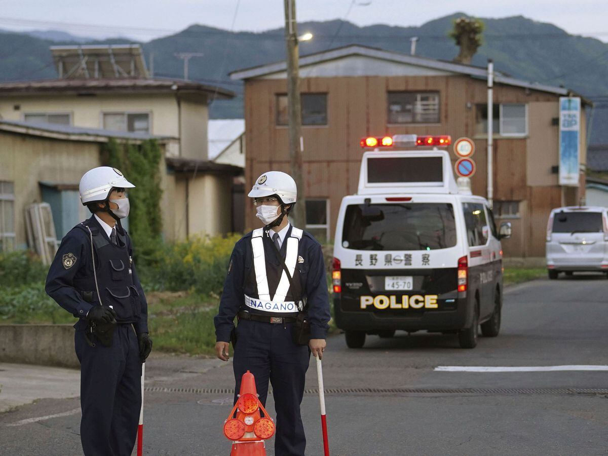 Police officers stand guard on a street leading to a building where a man was holed up in Nakano, central Japan