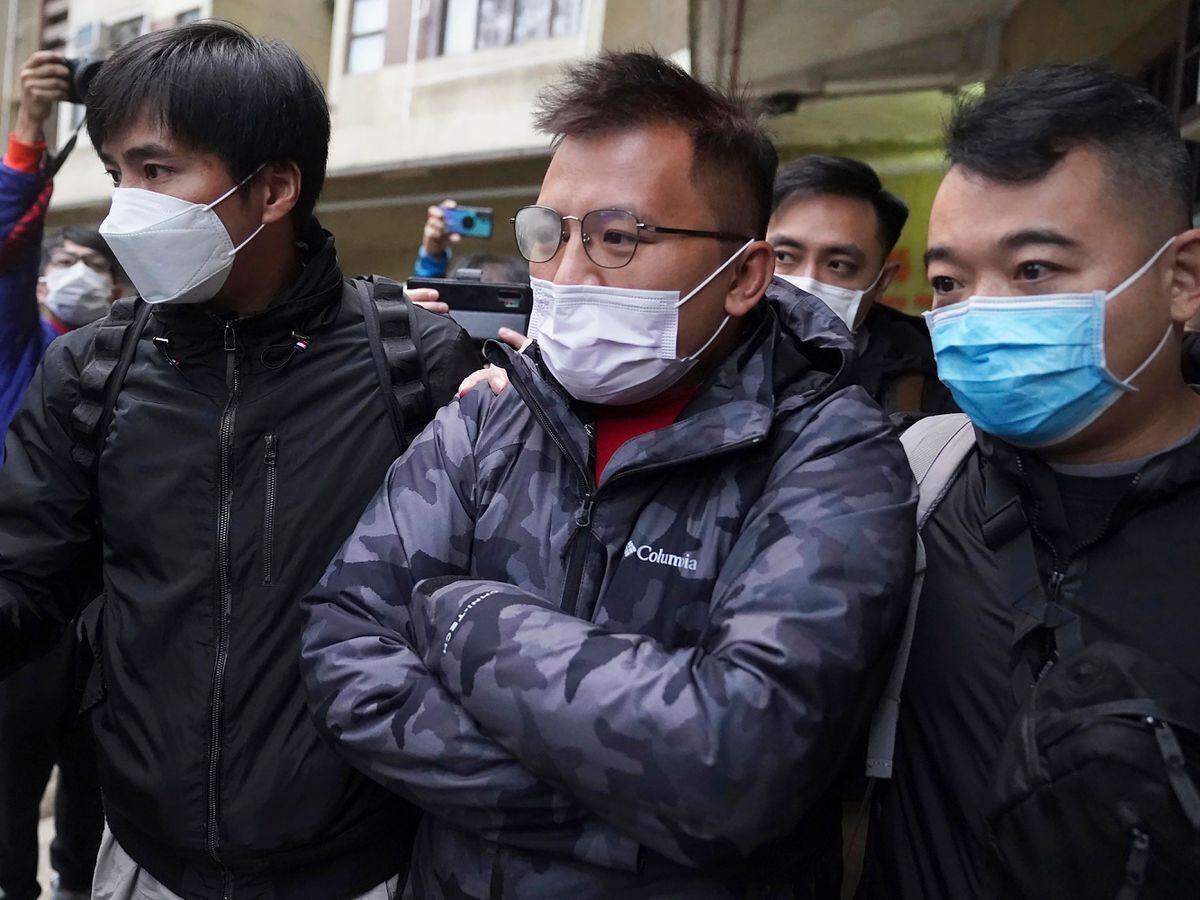 Senior editor of Stand News, Ronson Chan, centre, is arrested by police officers in Hong Kong