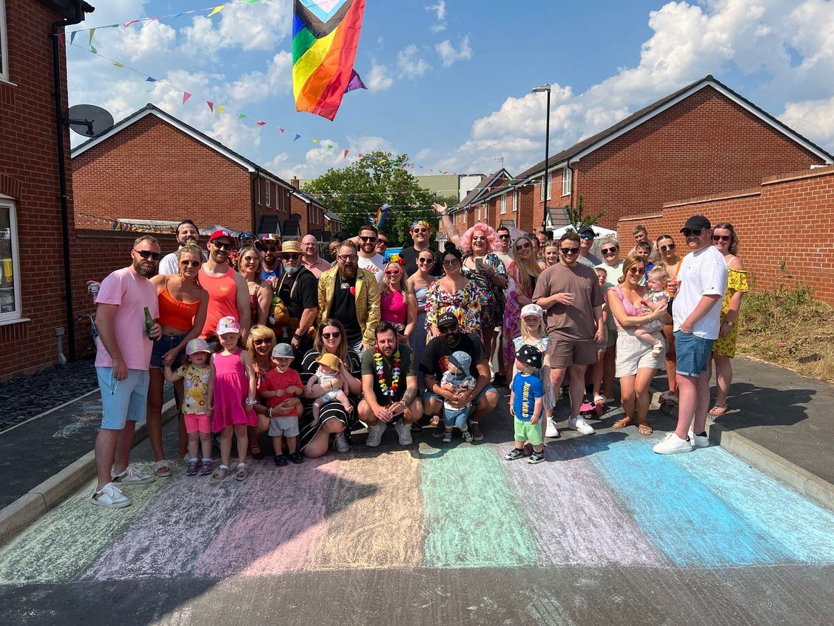 Residents of Batts Close, Rugby pose in front of a Pride flag drawn on the road