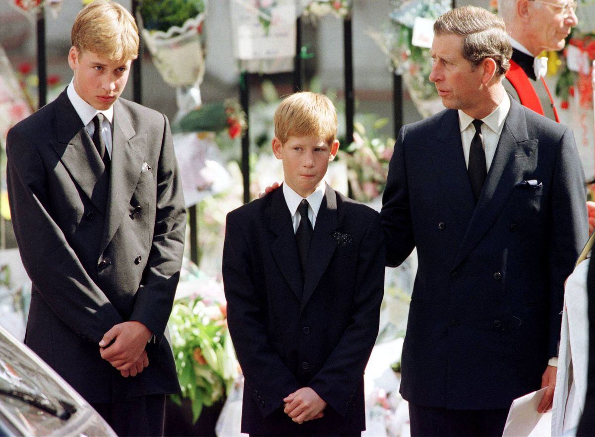 Prince Charles puts his hand on Prince Harry's shoulder as Prince William looks on after the coffin of Diana, Princess of Wales, was placed into a hearse