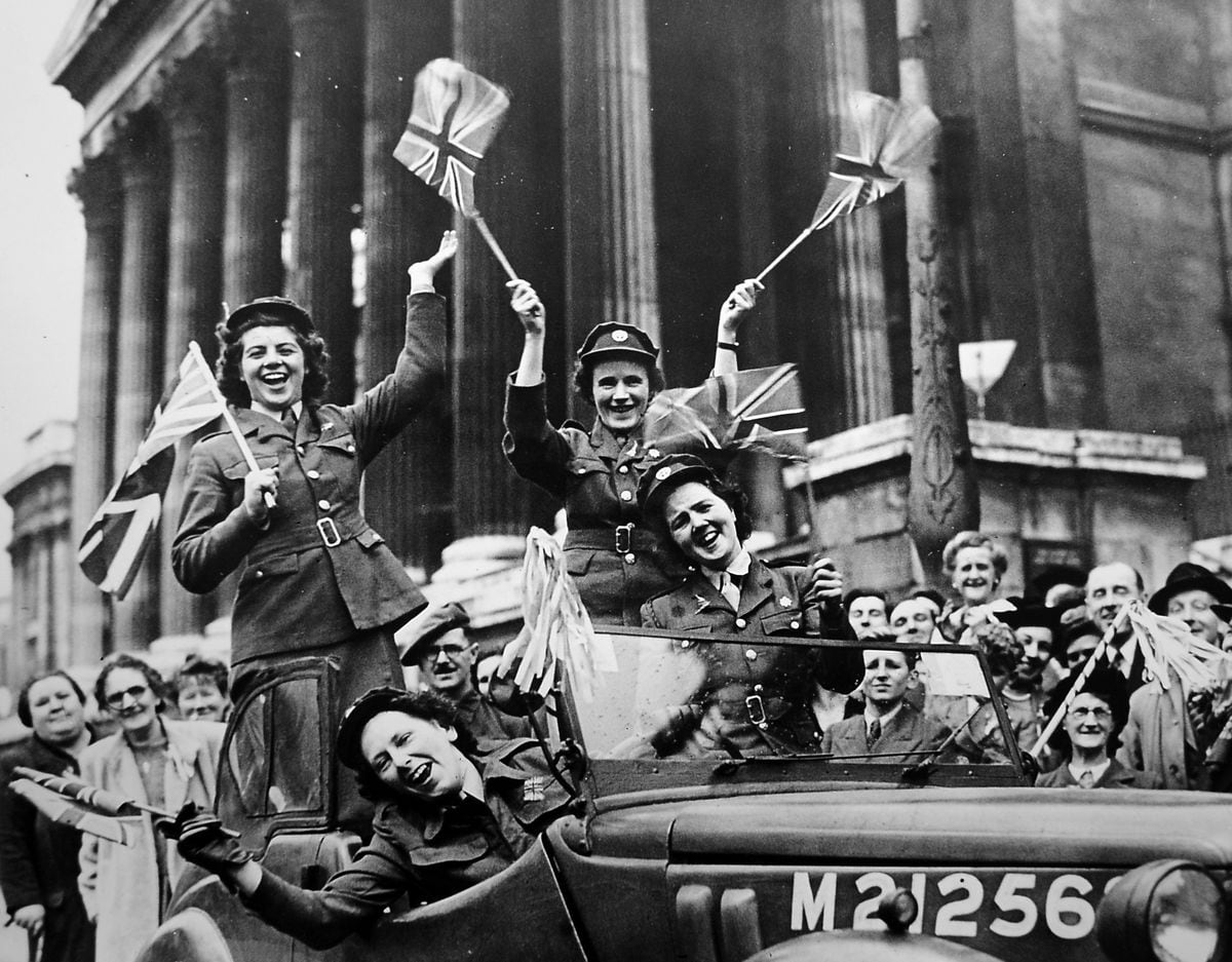 Girls of the Women's Royal Army Corps drive their service vehicle through Trafalgar Square waving flags in celebration of victory, May 8, 1945.