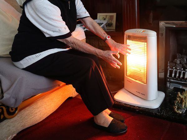 An elderly lady with her electric fire on at home