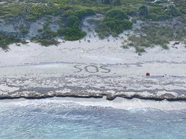 The letters SOS etched in the sand during the Coast Guard’s rescue