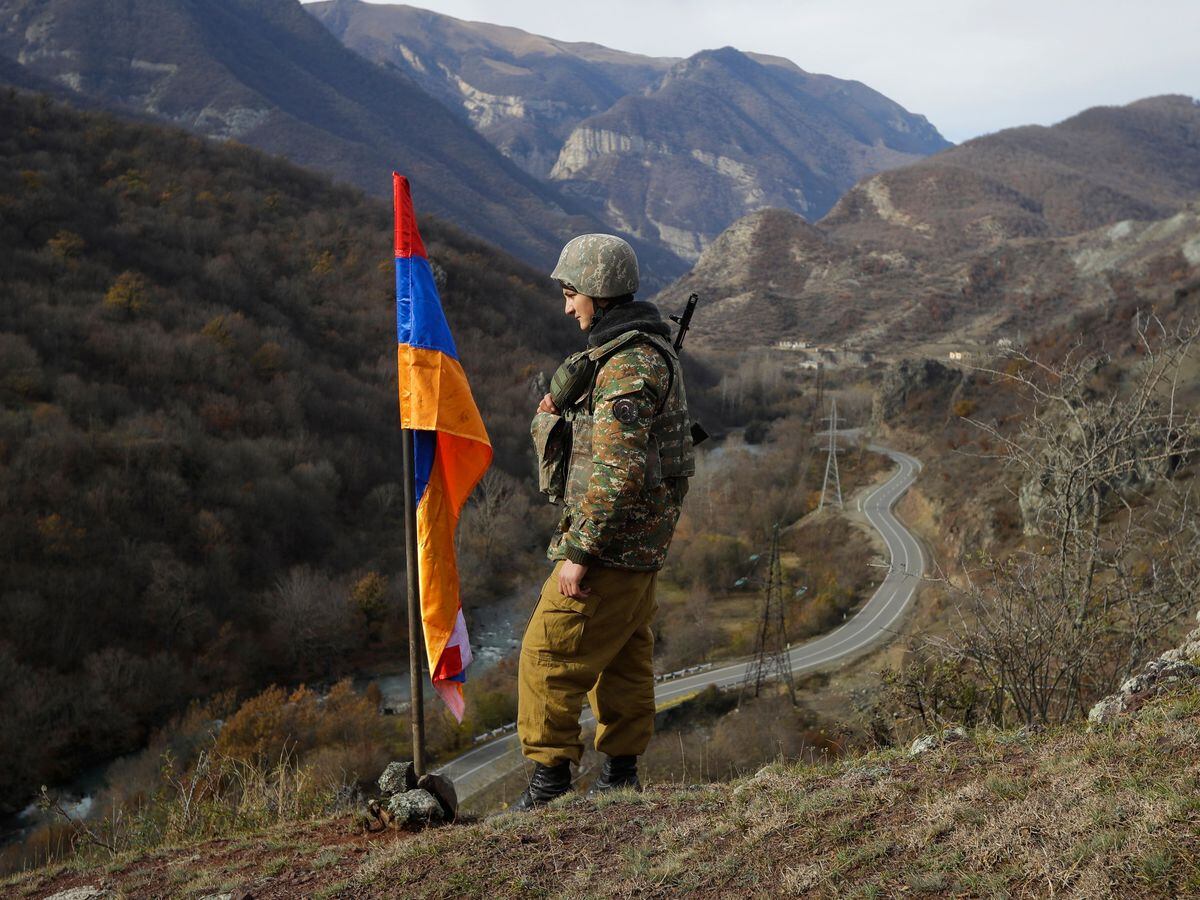 An ethnic Armenian soldier stands guard next to Nagorno-Karabakh’s flag atop of the hill near Charektar in the separatist region of Nagorno-Karabakh in 2020