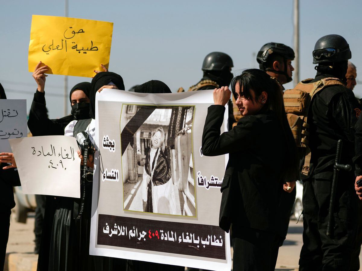 Demonstrators hold placards and a poster with a picture of Tiba Ali, a YouTube star who was recently killed by her father, in Diwaniya, Iraq
