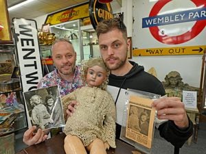 Phil and Liam Sims pose with the doll and photos of Doris with the doll