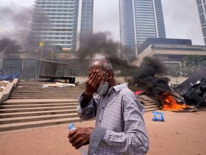 A Sri Lankan man reacts to tear gas as he walks past the vandalised site of anti-government protests outside the President’s office in Colombo, Sri Lanka, on Monday May 9 2022