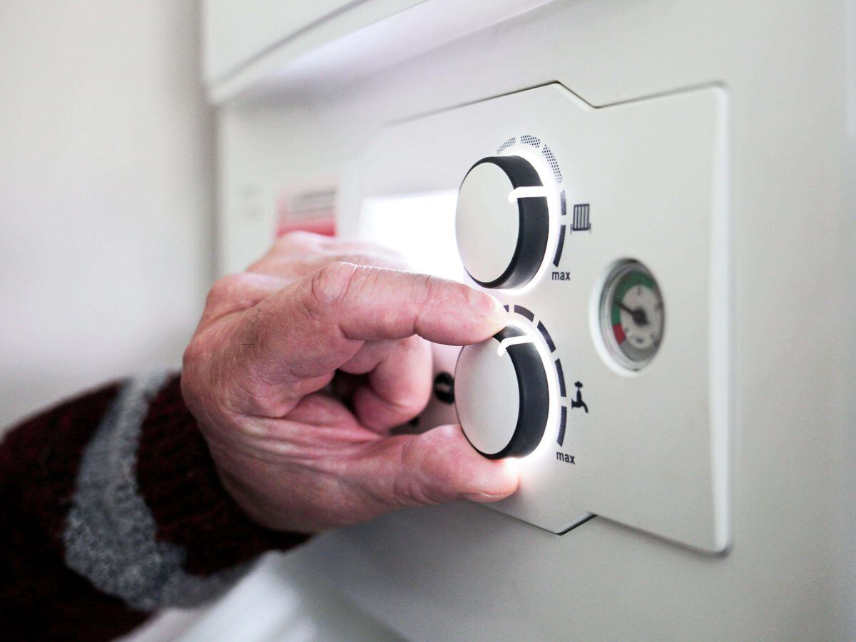 A pensioner adjusting the temperature control on his combi boiler