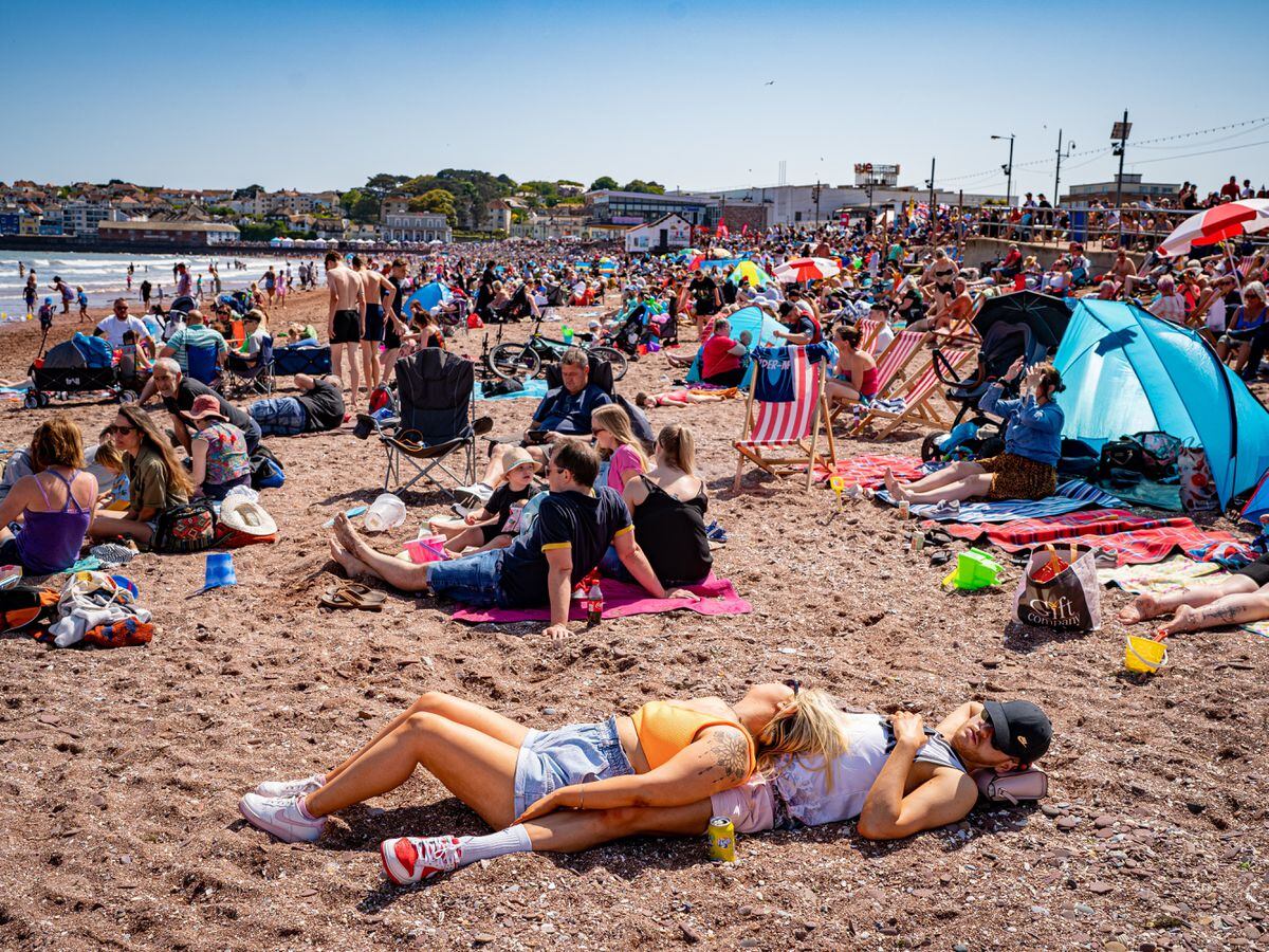 People sunbathing on a beach in June 2023
