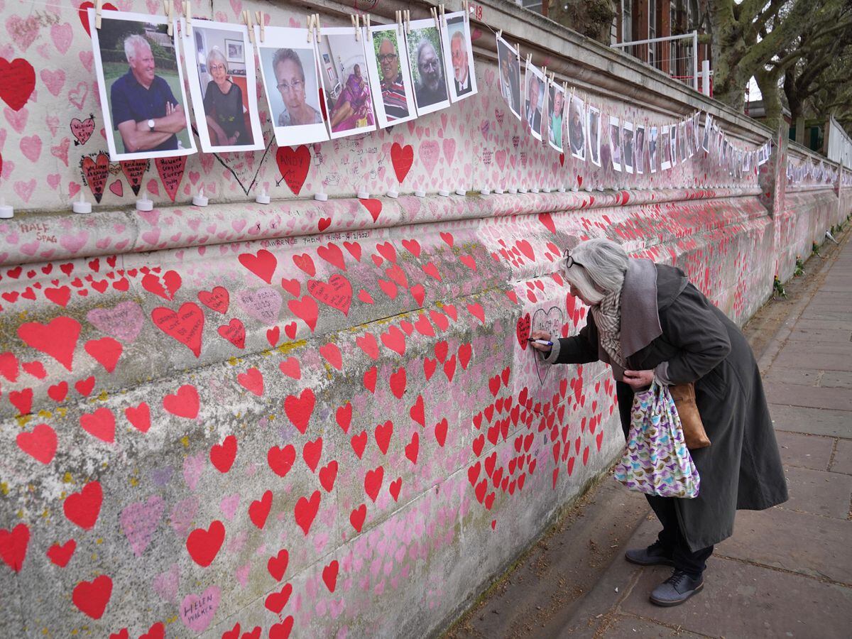 Photographs on the Covid memorial wall in London (Stefan Rousseau/PA)